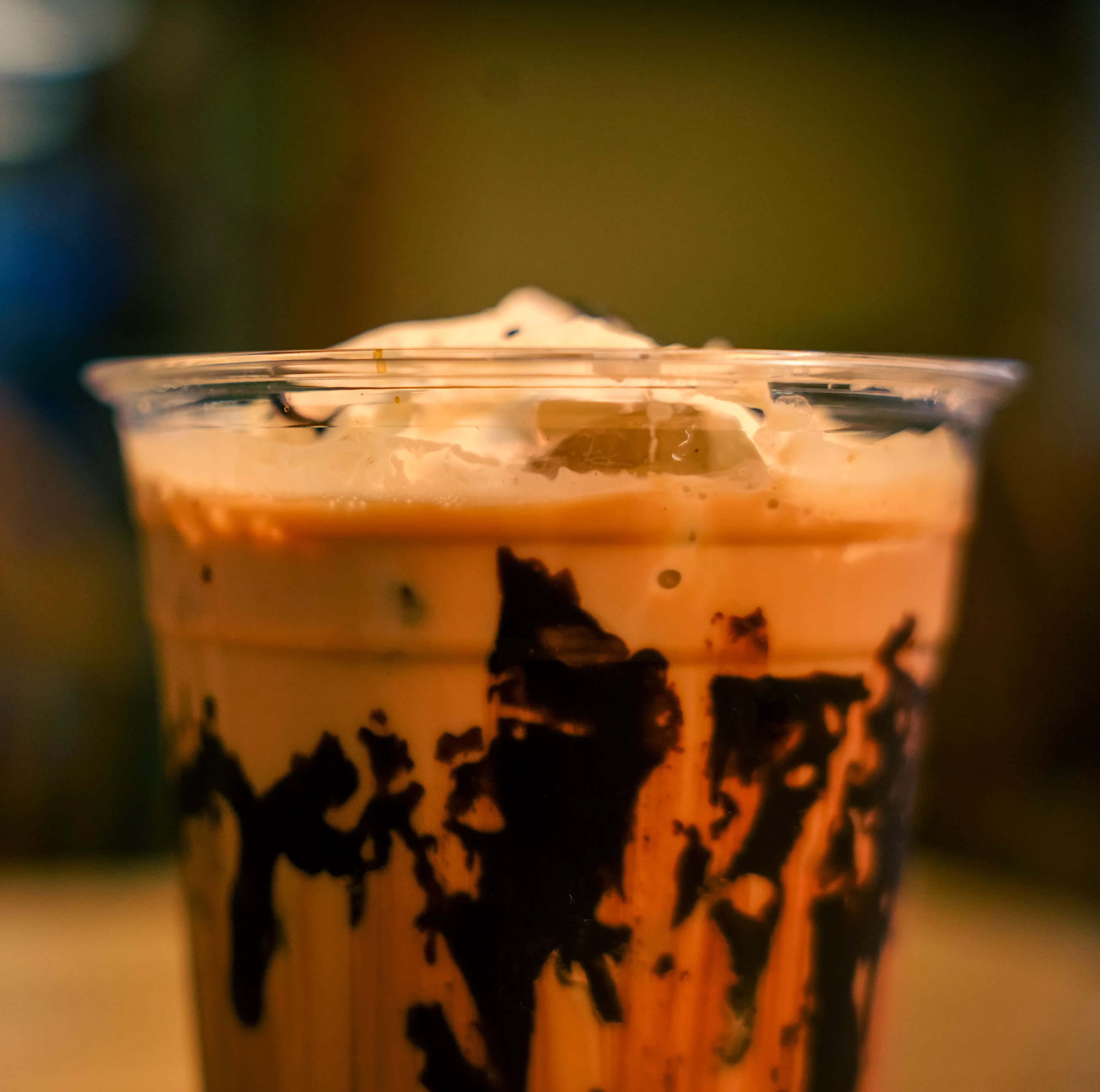 A plastic coffee cup with chocolate syrup around the sides.
